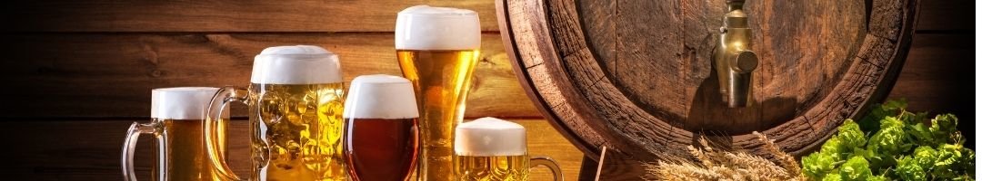 Verschiedene Biergläser mit Bier und einem Bierfass