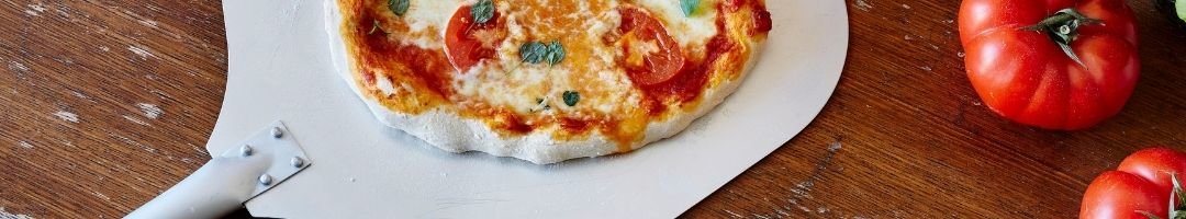 Pizza auf der Pizzaschaufel mit Tomaten