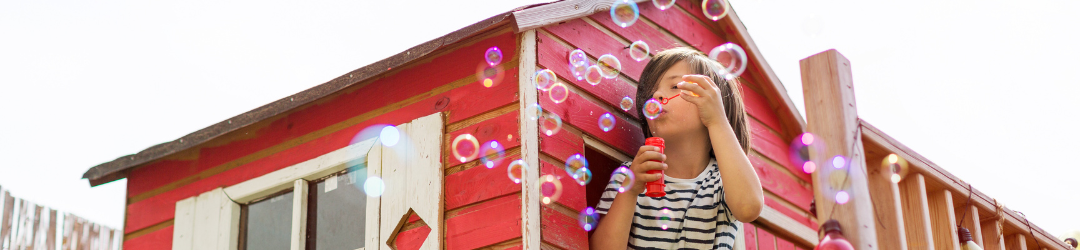 Junge spielt auf einem Spielhaus mit Seifenblasen