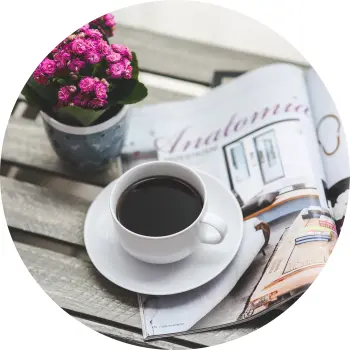 Kaffee in einer weißen Tasse auf einem kleinen Tisch mit lila Blumen