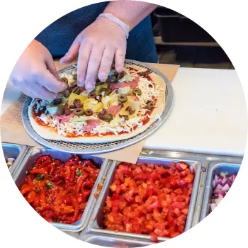 Leckere Pizza, die auf einem Pizzatisch vorbereitet wird