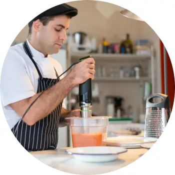 Koch, der mit einem Stabmixer Tomaten püriert